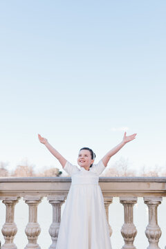Girl in a First Communion Dress Facing the Sky with Joy
