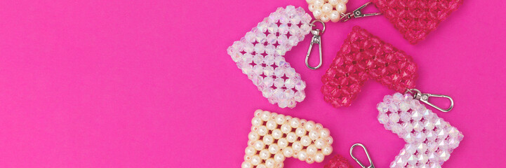 Banner with keychains in a heart shape made from beads on a magenta background.
