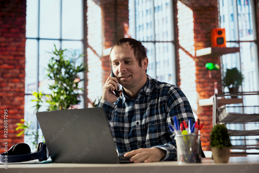 Aufkleber happy employee at desk using laptop excited to receive phone call from friend. cheerful man in home 