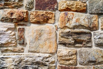 This image features a close-up of a rustic stone wall, showcasing the unique colors and textures of...