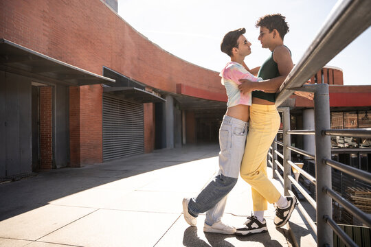 Gay couple embraces near brick wall outside train station
