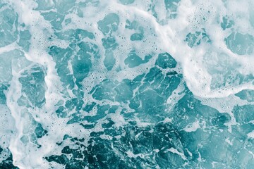 Obraz premium Gentle waves create white foam on the surface of turquoise ocean water, providing a serene and natural background perfect for various design projects