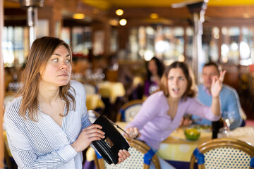 Female thief trying to steal handbag of frightened young woman in restaurant and escape..