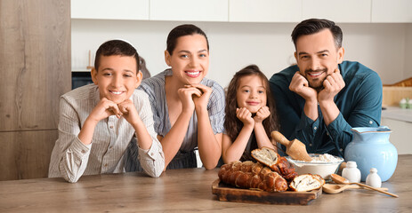 Happy Jewish family with challah bread at table in kitchen