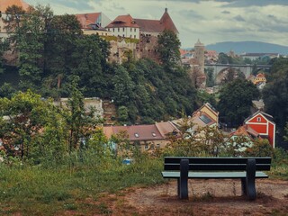 A peaceful viewpoint overlooking a historic European town with a medieval castle, colorful houses,...