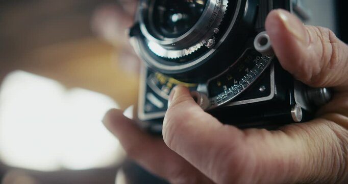 Detail of fingers pulling focus on a vintage camera.