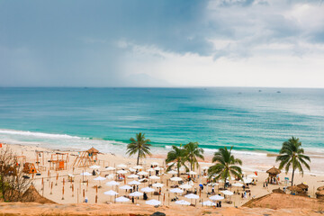 Elevated View of a Beach in South Lampung Turquoise Waters, Palm Trees, and Beach Umbrellas Under a Cloudy Sky