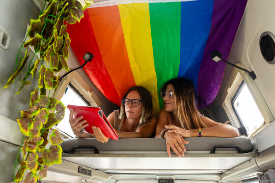 Couple in camper van enjoying digital content under flag