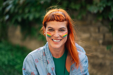 Portrait of smiling woman with rainbow flag painted on face