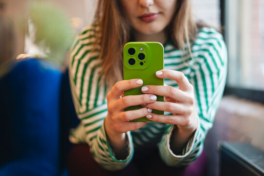 Anonymous woman using smartphone during coffee break in cafe