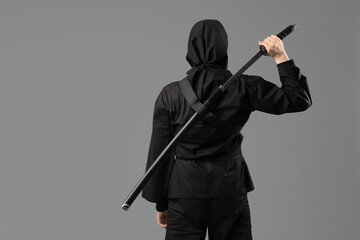 Male ninja with sword on grey background, back view © Pixel-Shot