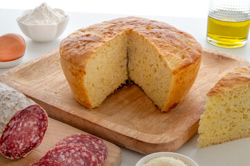 Traditional Easter pizza cake from central italy, with pamigiano cheese and pecorino romano cheese, accompanied by salami and eggs , horizontal close up photo with white wooden table 