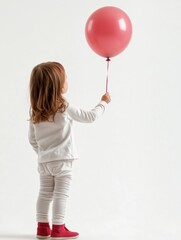 Young child grasping a floating balloon against a white background with soft lighting. AI generated