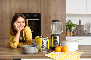 Young woman with modern appliances on wooden table in kitchen