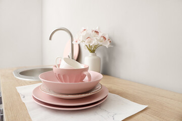 Clean dishes and vase with orchid flowers on kitchen counter, closeup
