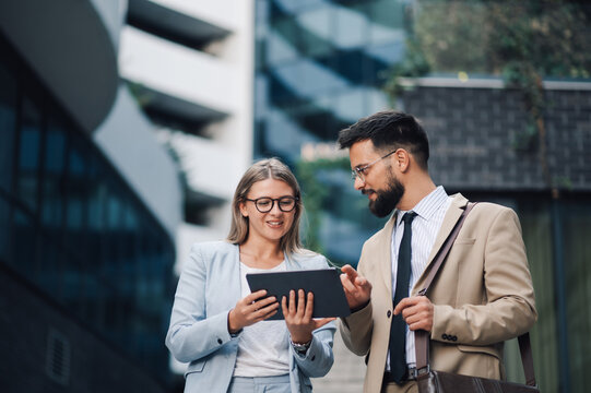 Business people having informal meeting using digital tablet outside office building