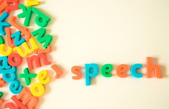 Speech word over warm white background formed from a bunch of scattered English Latin alphabet letters types. Oral communication, talk, speech therapy, expression and language concepts.