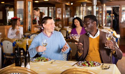 Meeting of two cheerful friends at dinner in a restaurant