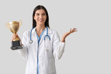 Female doctor with gold cup on light background