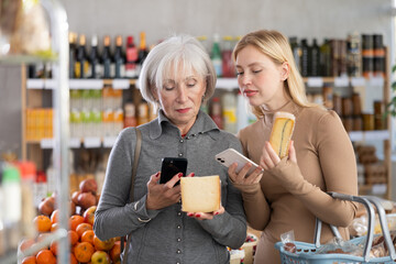 Elderly mother and her adult daughter scan a QR code on a cheese label together to check the expiration date