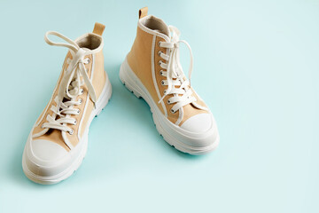 A pair of beige sneakers on an isolated blue background. Running shoes. 