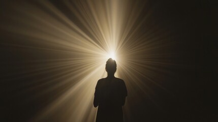 Silhouette of person in radiant light with uplifted arms