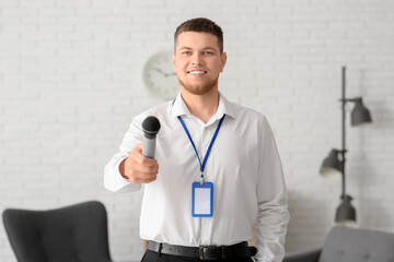 Male reporter with microphone and blank name tag taking interview in studio