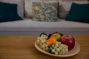 A vibrant and colorful fruit bowl placed on a wooden table in a cozy living room setting