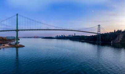 Panoramic view of the Lions Gate Bridge at twilight. City skyline reflected in the calm waters. Beautiful evening light.  Vancouver, British Columbia, Canada