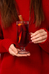 Young woman holding glass cup of hot mulled wine, closeup