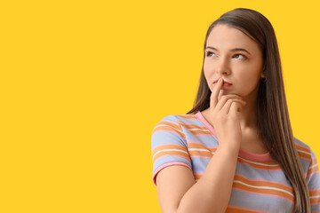 Wondering young woman on yellow background, closeup
