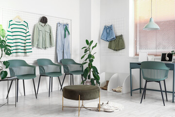 Interior of clothing store office with table, pin boards and chairs