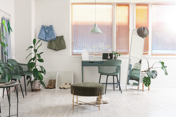 Interior of clothing store office with workplace, pin board and plants