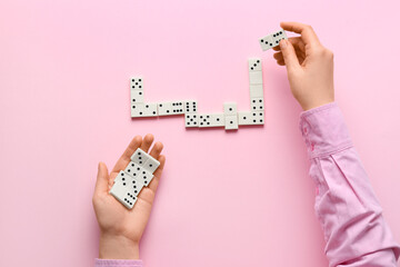 Woman playing dominoes on pink background, closeup