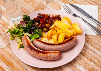 Appetizing grilled sausages served with fried potato, mushrooms and greens