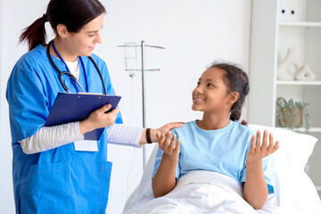 Teenage African-American girl talking to doctor in hospital room