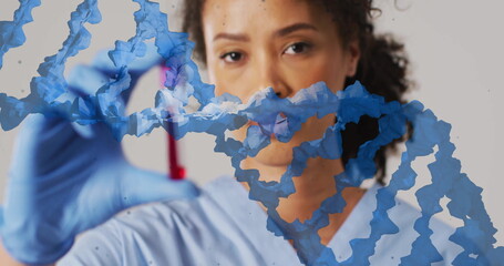 Image of blue dna strand over biracial female doctor holding blood sample