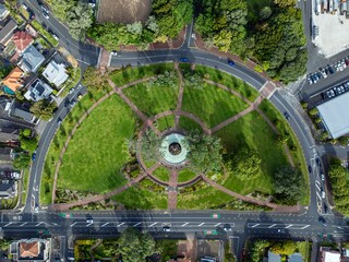 High-angle view of a park, surrounded by residential streets and a parking lot. Cars are visible on...
