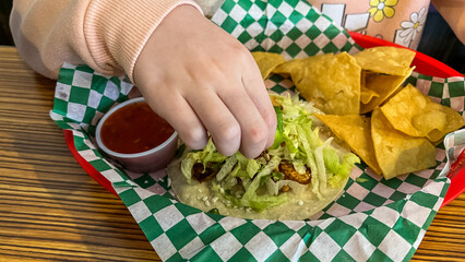 Child Eating Taco with Chips and Salsa