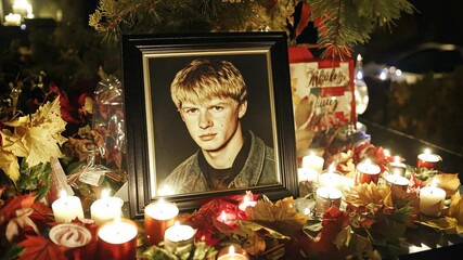 Memorial display honoring a young person with candles and flowers during an evening gathering