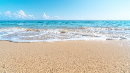 Fototapeta premium Calm ocean waves on sandy beach, sunny sky. Ideal for travel, vacation brochures
