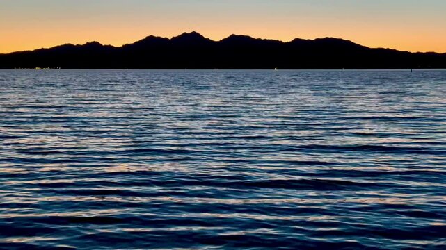 Breathtaking sunset paints the sky in vibrant hues over Lake Havasu, casting a golden glow across the tranquil waters as the California shoreline silhouettes against the horizon.