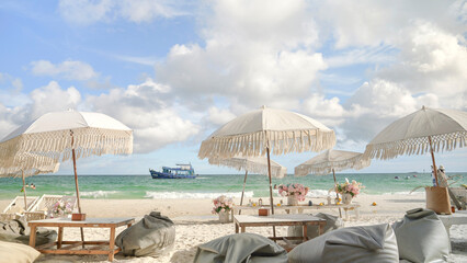 Beachside lounge featuring elegant bohemian-style umbrellas with fringe details, wooden tables and cozy bean bags. © Artstore Studio