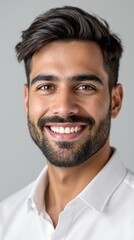 Obraz premium Confident young man smiling in white shirt against gray background
