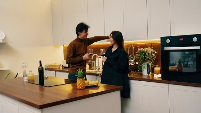Couple enjoying a cozy evening with wine in a modern kitchen in fall