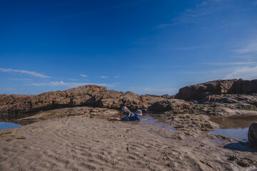 Two kids playing in rock pools