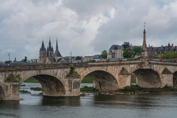 View of the embankment with ancient houses and the Jacques Gabriel Bridge over the Loire River on a sunny summer day, Blois, Loire and Cher, France