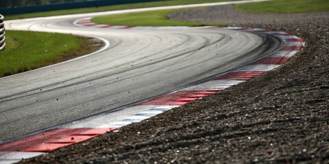 Curved racetrack at high-speed motorsport event with tire marks and gravel
