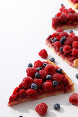 Pieces of berry pie and berries on white background, space for text