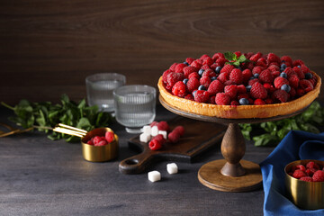 Berry pie, mint, kitchen board and glasses on wooden background, space for text